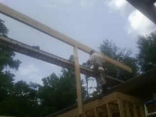 Carpenter setting a ridge beam over a new addition frame — Ice Dam Removal by Roofing Brothers in Cliffside