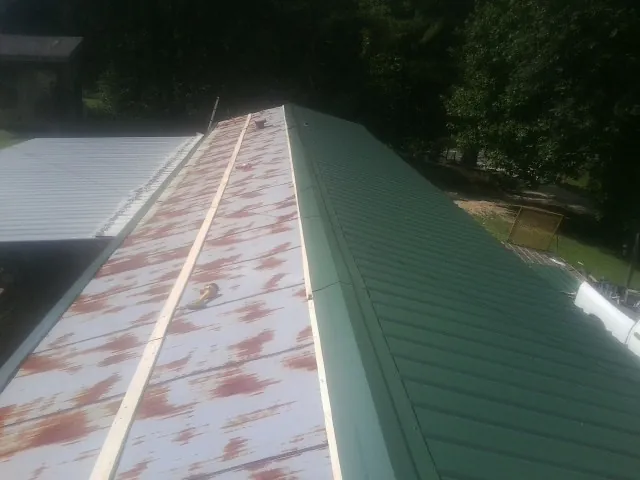 Old rusted panels beside newly installed green metal roofing — Wind Damage Roof Repair by Roofing Brothers in Cliffside