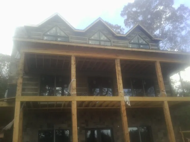 Dormers and porch framing on a large log home under construction — Roof Coating work by our crew in Cliffside