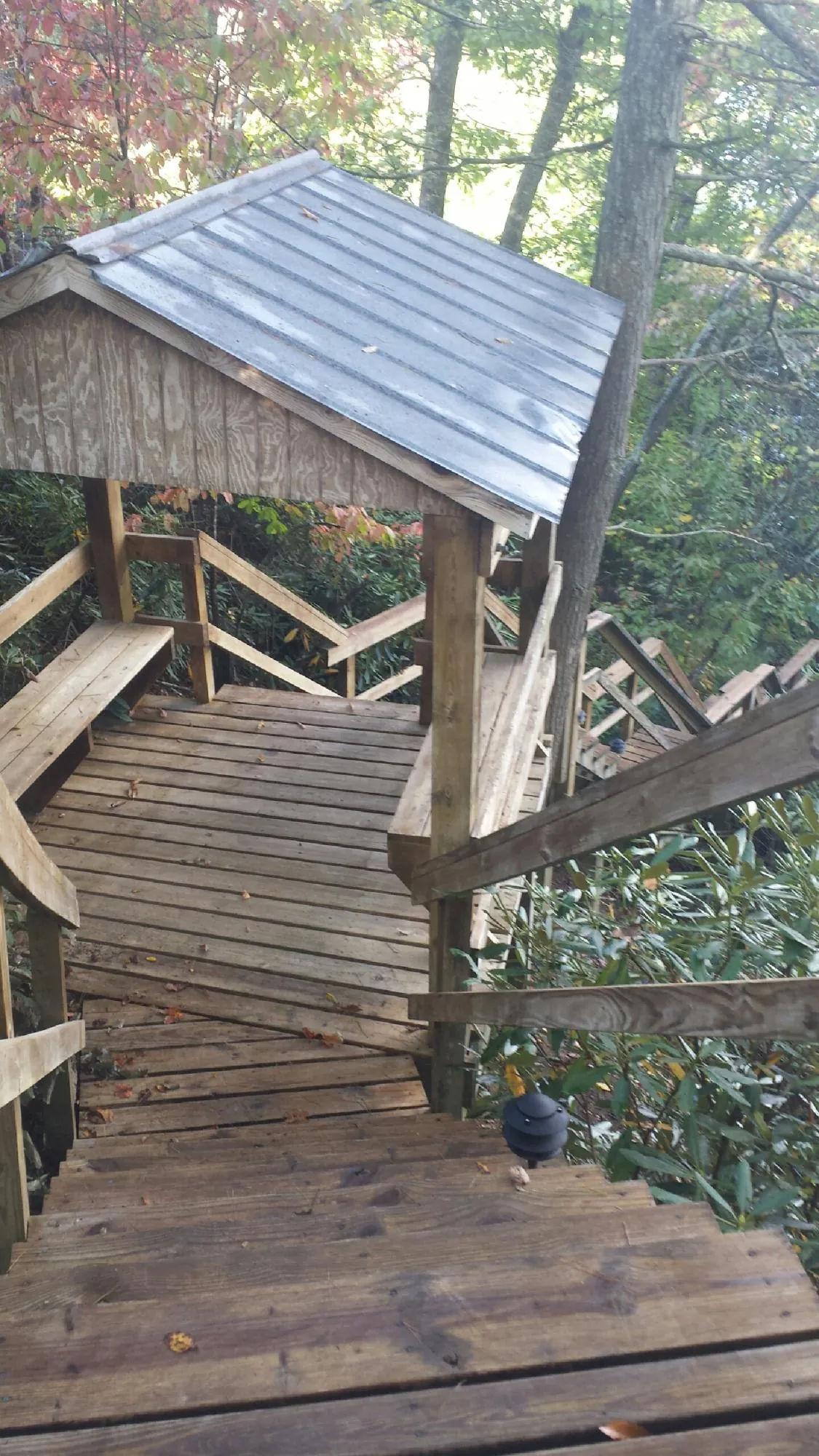 Metal roofed shelter over wooden steps on a wooded walkway — Skylight Repair & Installation work by our crew in Cliffside